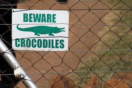 A warning sign of crocodiles on a metal fenceの写真素材