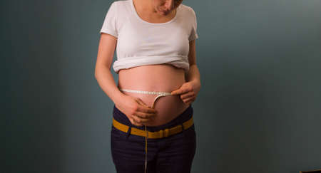 A pregnant woman measuring her belly