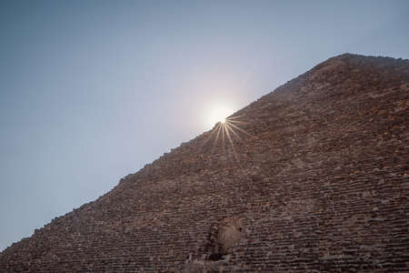 A low angle shot of the sun shining from behind the Great Pyramid of Giza in Egyptの写真素材