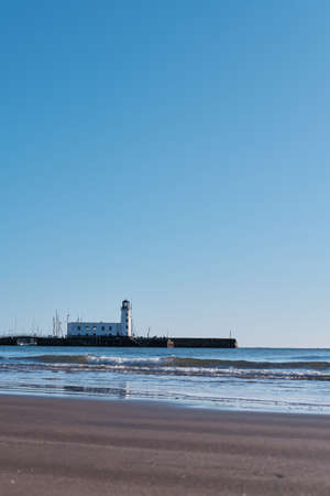 SCARBOROUGH, UNITED KINGDOM - Jan 18, 2020: Vertical shot of the lighthouse on the coast of scarborough in north yorkshire on a bright cold cloudless sunny day in Januaryのeditorial素材