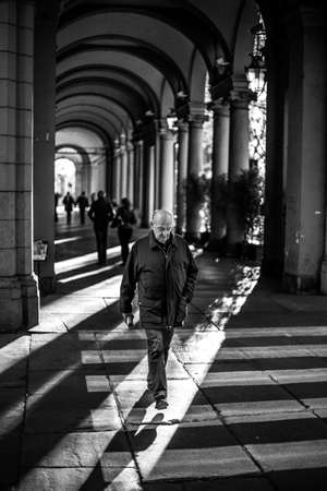 TURIN, ITALY - Oct 20, 2016: black and white of a Turin street with various lines of light and shadows, having an elderly person in the foregroundのeditorial素材