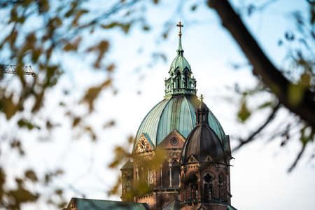 A wide angle shot of the upper part of a building behind a tree branchの写真素材