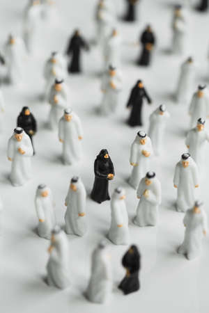 A selective focus shot of small statues of Muslim people with men in white robes and women in blackの写真素材