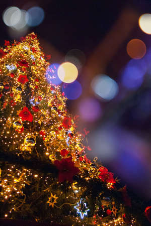 A low angle shot of a bright christmas tree full of beautiful decorations with a blurred backgroundの写真素材