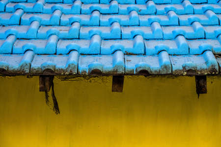 A closeup shot of the yellow wall and the blue roof of a building
