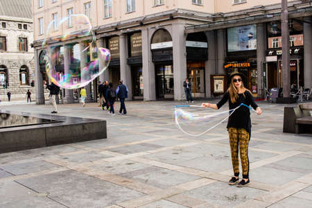 BERGEN, NORWAY - Aug 01, 2019: A female street performer creates large bubbles in the main city square of Bergen, Norway.のeditorial素材