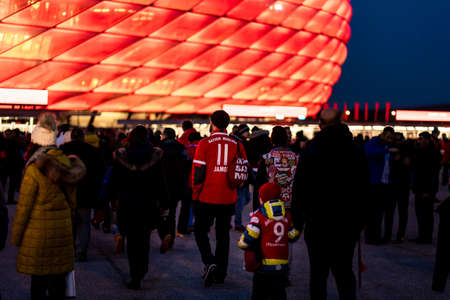 MUNICH, GERMANY - Jan 25, 2020: Fans of german soccer club FC Bayern Munich walking to home stadium. Matchtime. Illuminated red arena due to evening night game.のeditorial素材