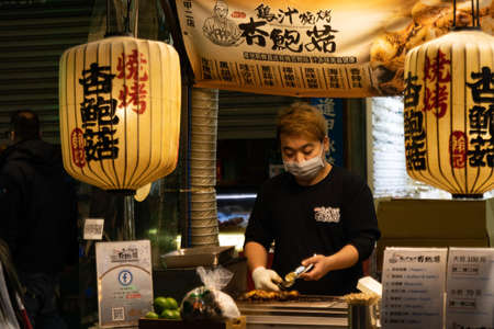 TAICHUNG CITY, TAIWAN - Jan 14, 2020: A Chinese man serves grilled food at Feng Chia Night Market in Taichung City in Taiwan - January 2020.のeditorial素材