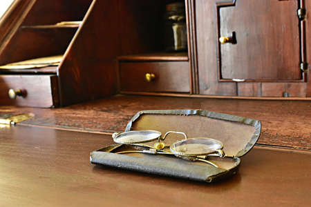 GLENDALE, UNITED STATES - Oct 18, 2019: An old wooden antique desk with the owner's spectacles lying and waiting.のeditorial素材