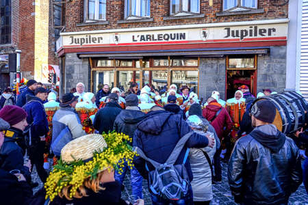 BINCHE, BELGIUM - Feb 18, 2018: Rassemblement de Gilles de Binche avec public en avant-plan montrant une participante portant un chapeau ornÃ© de mimosaのeditorial素材