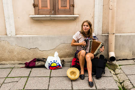 TALLIN, ESTONIA - Sep 05, 2019: A female street musician plays the accordion on a side walk in the old town of Tallin in Estonia.のeditorial素材