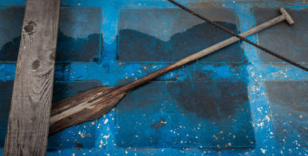 The view inside a blue boat with a wooden paddle on the groundの写真素材
