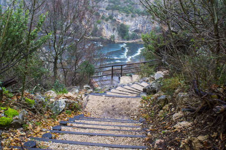 A staircase surrounded by the river and rocks covered in greenery in Krka National Park in Croatia
