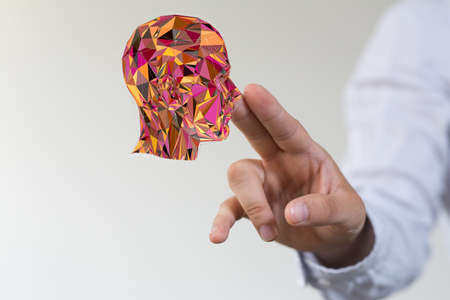 A human hand presenting a colorful digital puzzle projection of a human headの写真素材