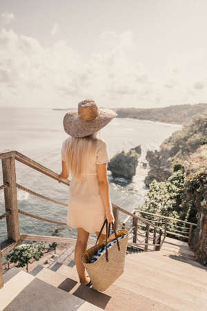 A vertical shot of a woman walking down the stairs with a handbag next to the beachの写真素材