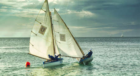A shot of people on the white boats swimming in the sea during cloudy weather