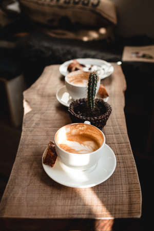 A vertical shot of coffee and a cactus on the tableの写真素材