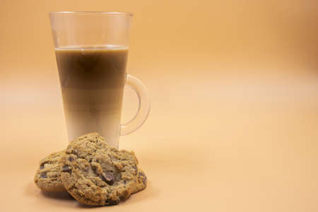 A studio shot of three layered tea drink and chocolate chip cookies in orange ombre backgroundの写真素材