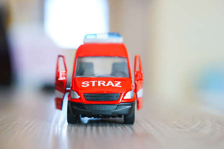 POZNAN, POLAND - Mar 27, 2016: Red fire department toy bus on wooden table in soft focus background.
