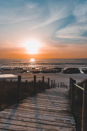 The mesmerizing view of the boardwalk near the shore during sunsetの写真素材