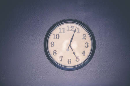 A watch hanging on the wall displaying five o'clock