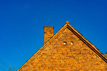A beautiful shot of a roof of a building made of red bricks with a blue sky in the backgroundの写真素材