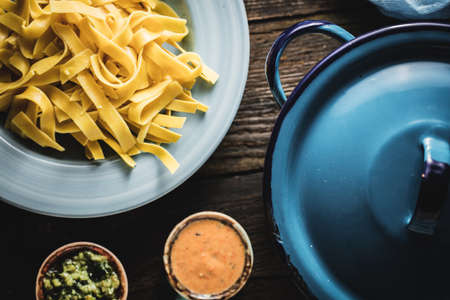 A top view shot of fettuccine with sauces and a blue pan next to itの写真素材