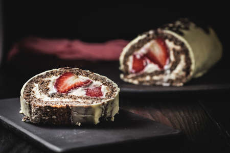 A closeup shot of chocolate roulettes with icing and creamy strawberries insideの写真素材