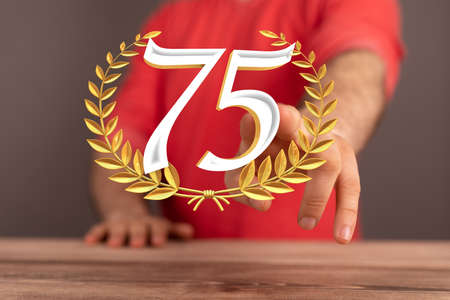 The number 75 and golden spikes of wheat over someone's hands