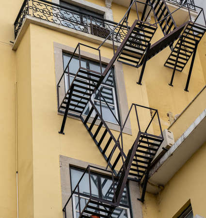 A low angle shot of a series of fire escape staircase outside a yellow building