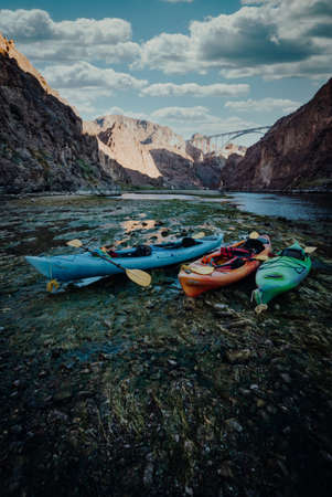 A vertical shot of colorful kayak boats on the shore of the lake in the mountains
