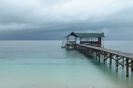 A pier with a gazebo on the sea under the cloudy sky - great for backgrounds and wallpapers