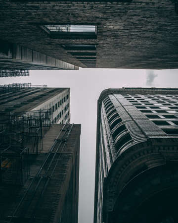 The low angle shot of the high buildings with metal stairs on a gloomy day