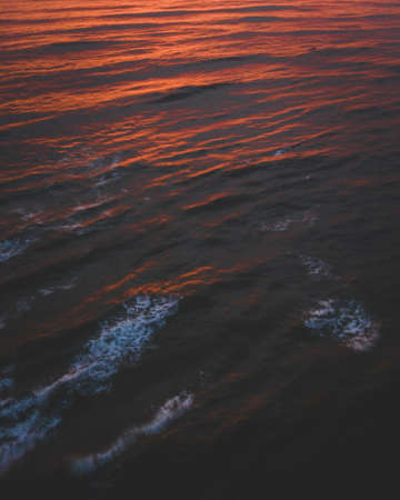 The beautiful shot of the calm ocean reflecting the colorful sky during sunsetの写真素材