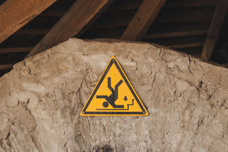 A closeup shot of a yellow traffic sign on a cliff turned upside downの写真素材