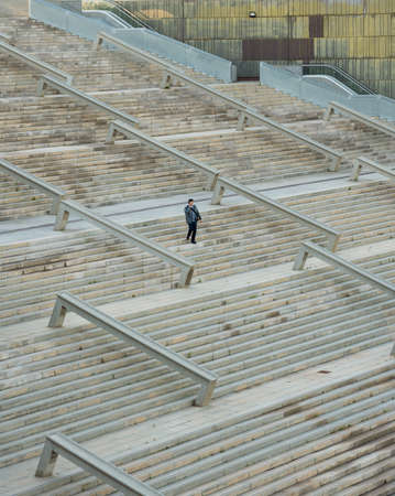 A high angle vertical picture of a man descending the stairs under the sunlightの写真素材
