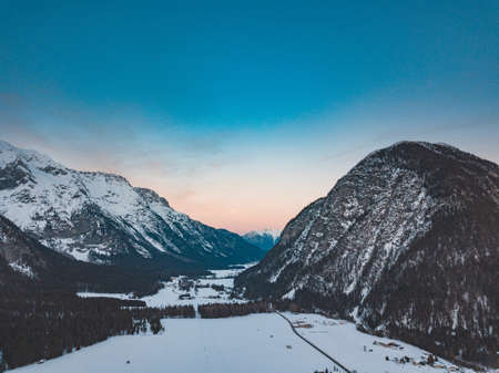 A stunning view of a mountain range in a cold and snowy day during sunsetの写真素材