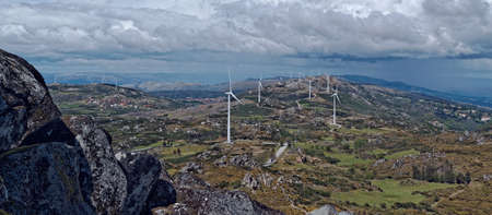 A wide angle shot of several wind fans on a large grassland during daytime