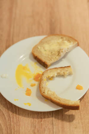 leftovers from a breakfast meal with a piece of loaf, loaf crust and yolk