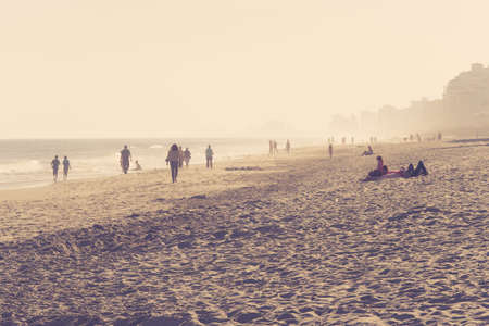 A beach shore with people walking around on a sunny dayの写真素材