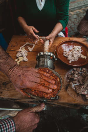 A high angle view of people grinding meat for a kielbasa with an old fashioned grinder on the tableの写真素材