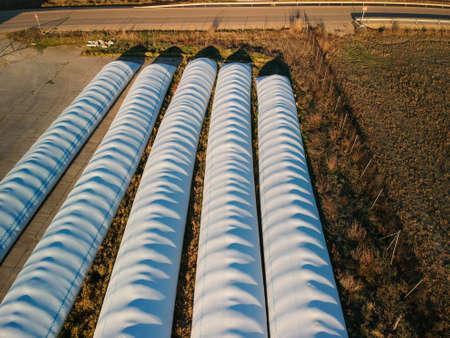 Aerial picture of five semi cylinders of wrapped forage in a field