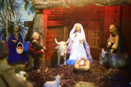A closeup shot of small statues of the bride, baby, animals and other men in a wooden roomの写真素材