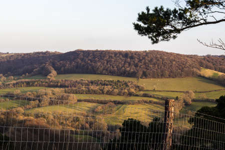 A high angle shot of the countryside with wide fields and wooded area