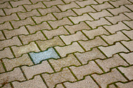 A high angle shot of a blue tile surrounded by others of grey color on the groundの写真素材
