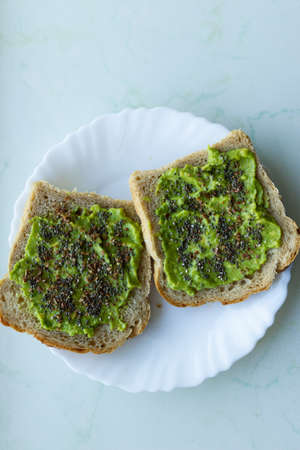 A high angle shot of bread with a spread of delicious avocado cream with chia seeds