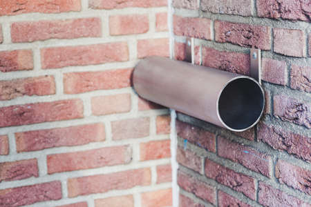 A metal round mailbox mounted on a wall in soft focus