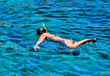 A young female in a swimsuit swimming in the sea on a sunny day - healthy lifestyle conceptの写真素材