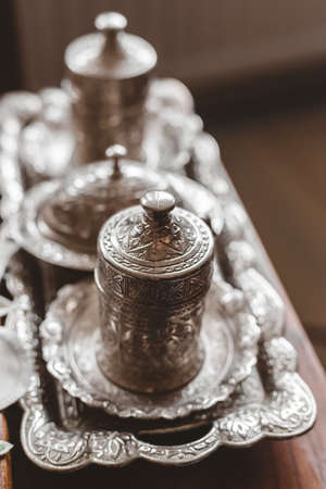 A vertical closeup shot of an antique silver tea set with a blurry backgroundの写真素材