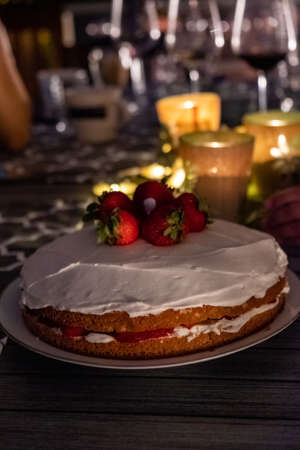 A closeup shot of a strawberry shortcake on an outdoor dinner table